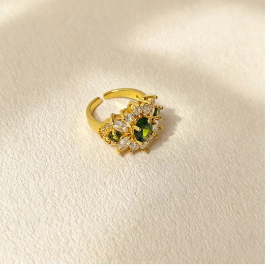 Side view of gold copper statement ring, green cubic zirconia stones, open band