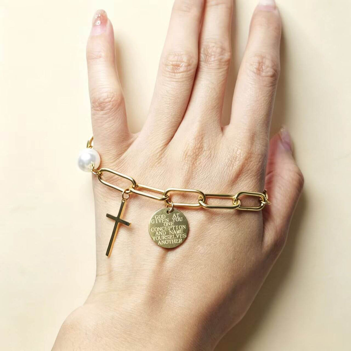Women wearing 18K gold faith bracelet with cross pendant and engraved coin charm