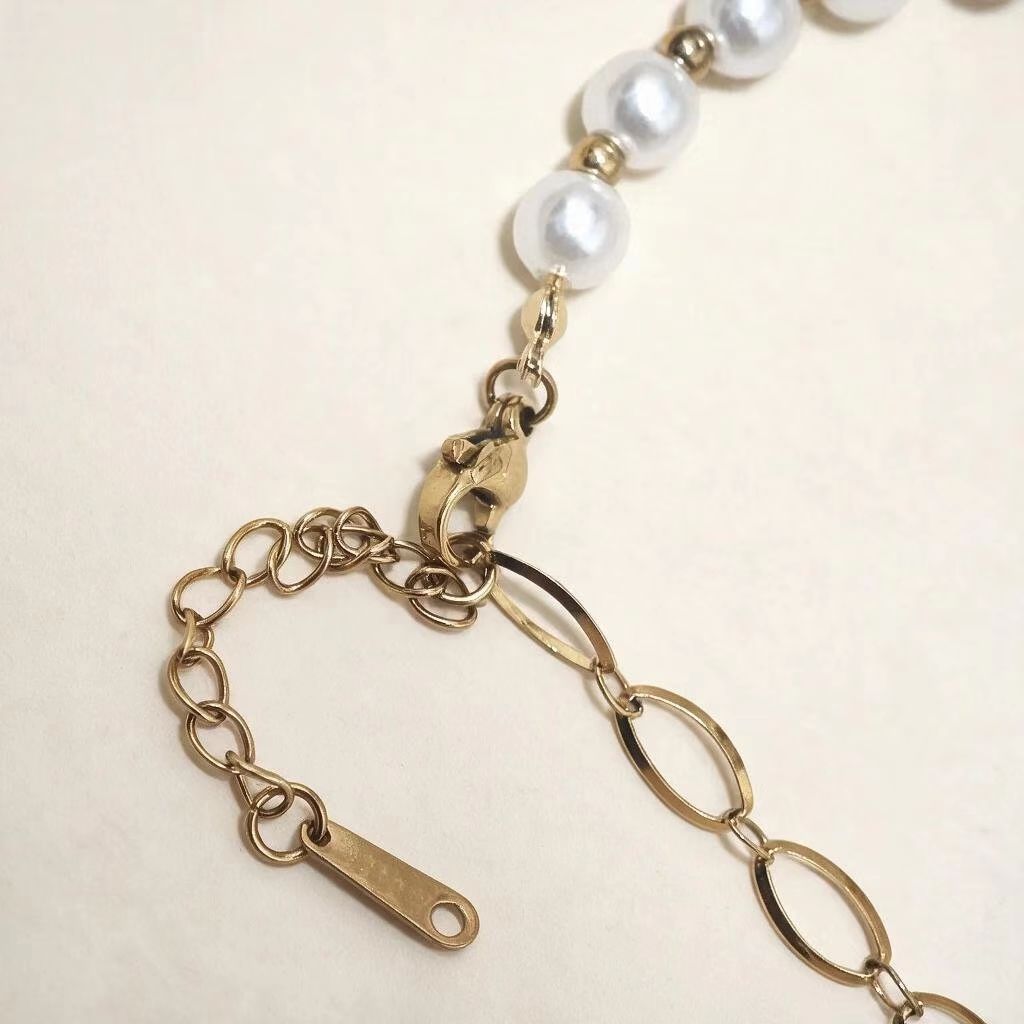 Close-up view of PVD gold stainless steel bracelet clasp and extender chain, faux pearl jewelry